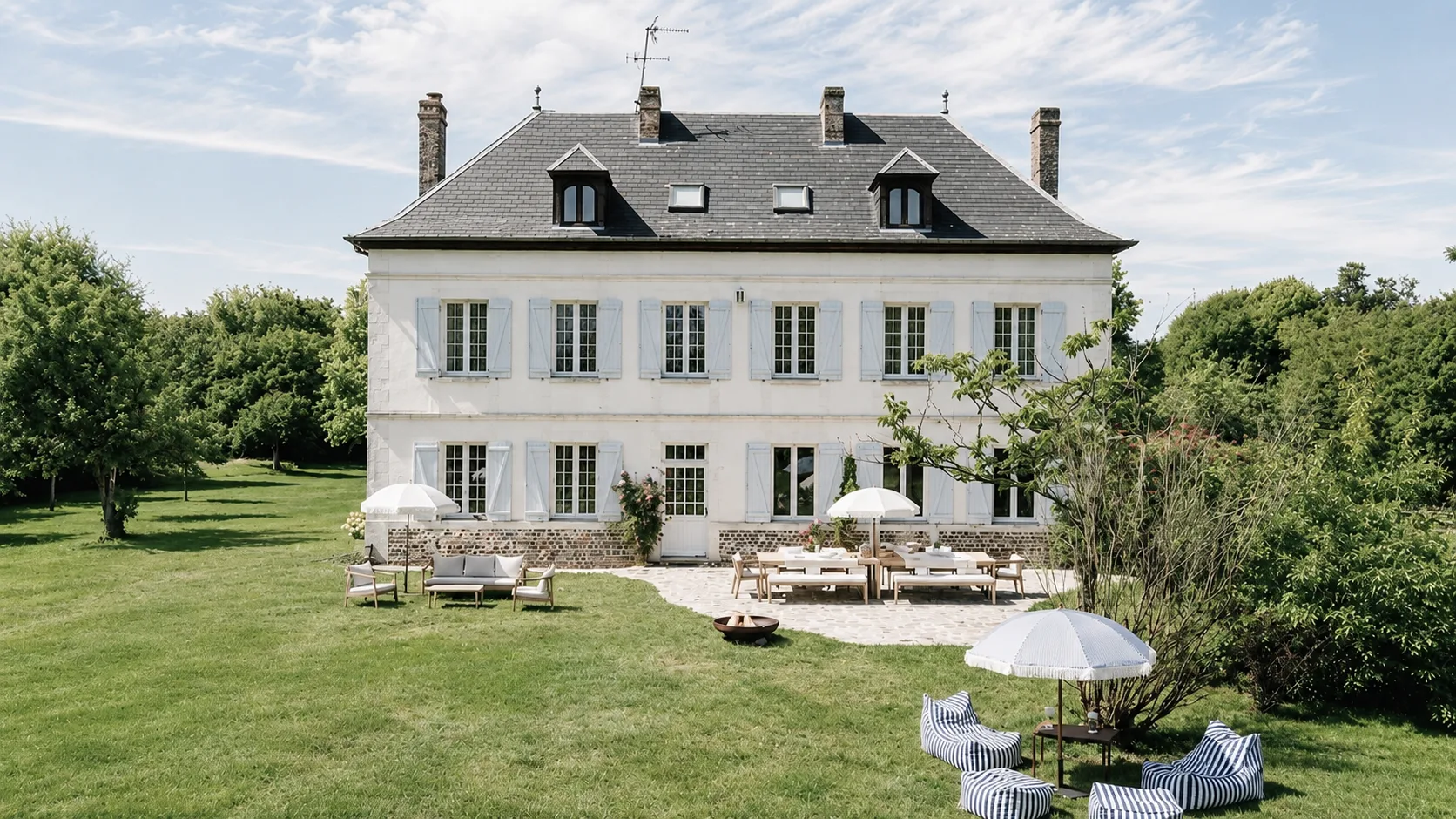 La façade de la maison de maître, parasols sur la pelouse